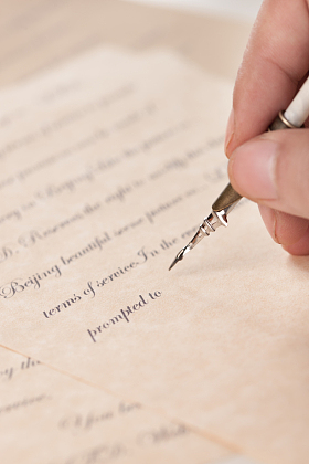 男人的手拿着鹅毛笔在写字图片