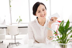 青年女人在办公室里拿着手机图片