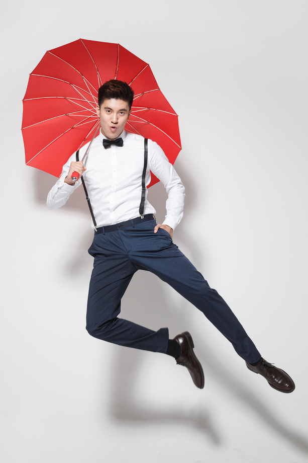 青年男人拿着心形红雨伞跳跃