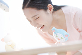 年轻妈妈在婴儿床旁照片