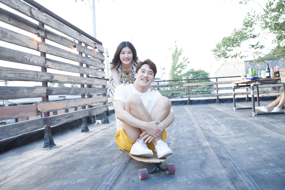 青年女人推着滑板车上的男友 青年女人推着滑板车上的男友