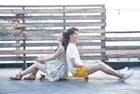 青年情侣坐在滑板上