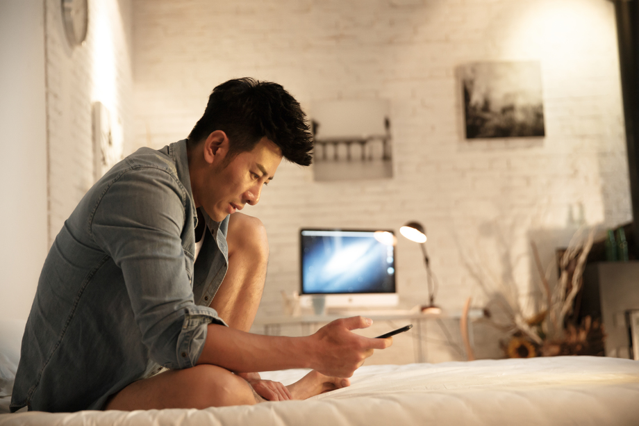 青年男人在卧室玩手机照片