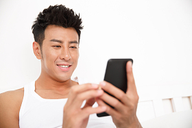 青年男人在卧室玩手机图片