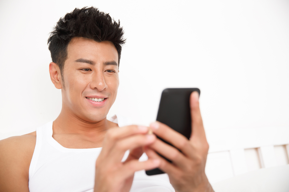 青年男人在卧室玩手机图片