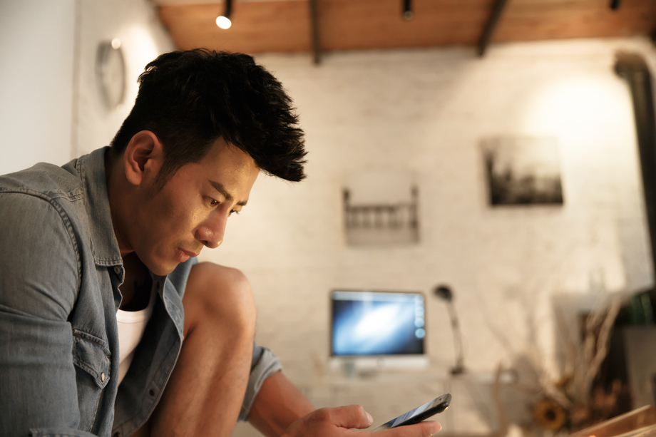 青年男人在卧室玩手机照片