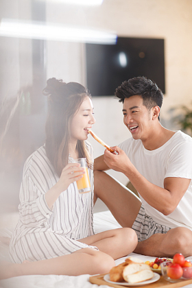 青年情侣在床上吃早餐照片