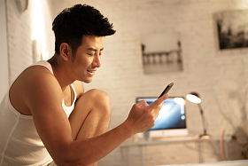 青年男人在卧室玩手机照片