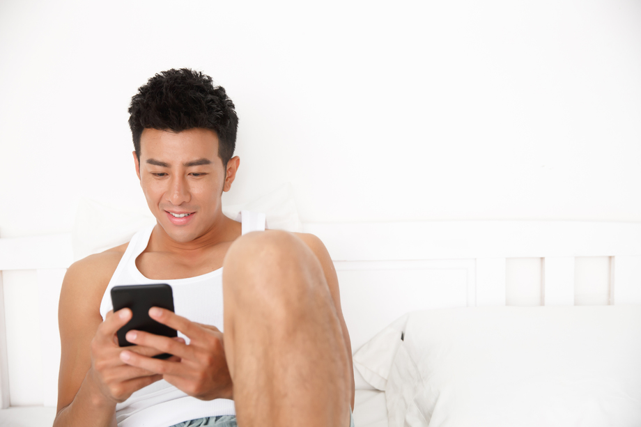 青年男人在卧室玩手机图片