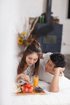 青年情侣在床上吃早餐照片