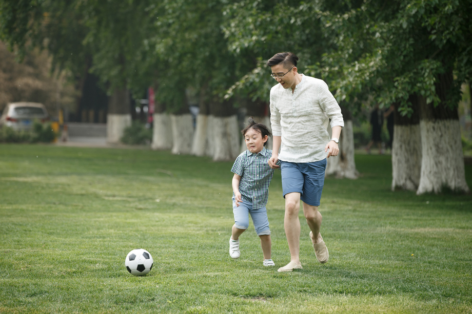 快乐父子在草地上踢足球照片 快乐父子在草地上踢足球照片