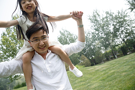 父亲驮着女儿在户外玩耍