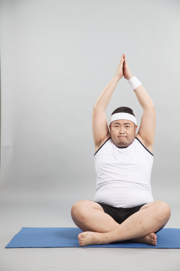 肥胖的青年男人在做瑜伽图片