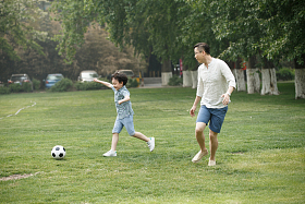 快乐父子在草地上踢足球照片