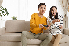 青年情侣坐着沙发上玩游戏图片