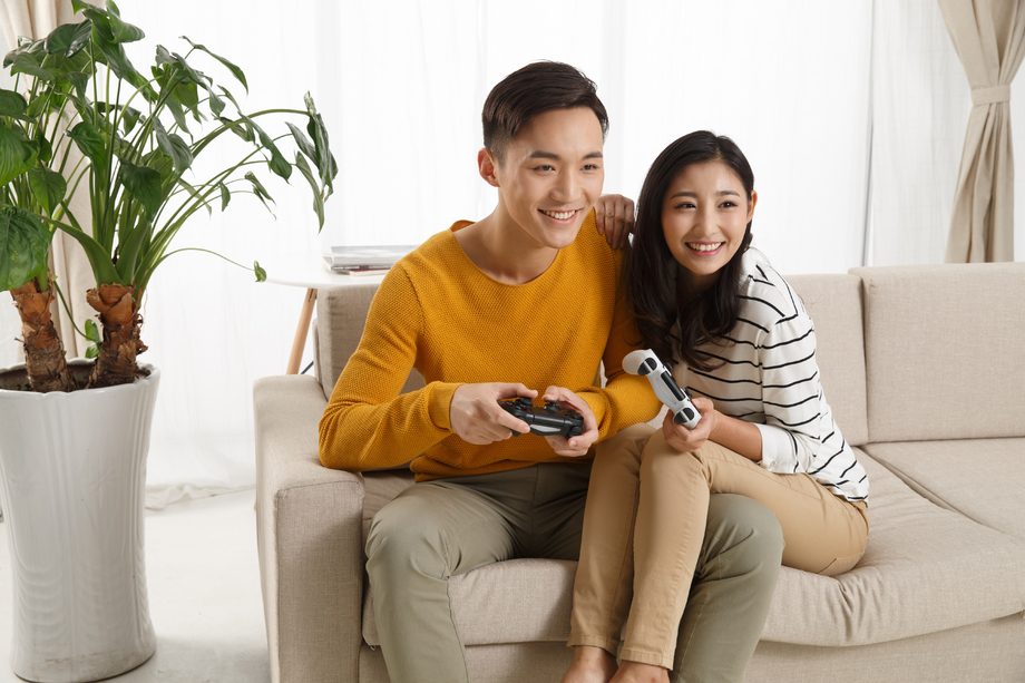 青年情侣坐着沙发上玩游戏图片