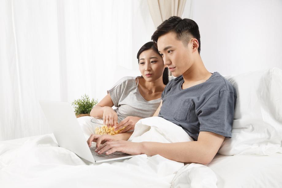 青年情侣坐着床上看电脑图片