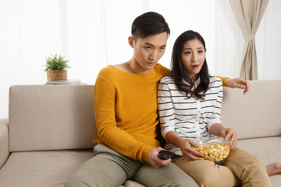 青年情侣坐着沙发上看电视