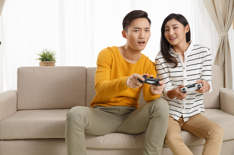 青年情侣坐着沙发上玩游戏照片