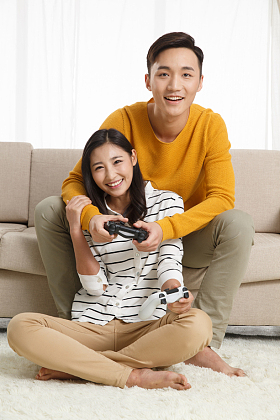 青年情侣坐着沙发上玩游戏图片