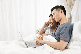 青年情侣坐着床上看电脑图片
