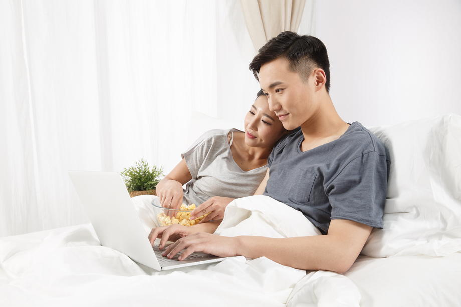 青年情侣坐着床上看电脑图片