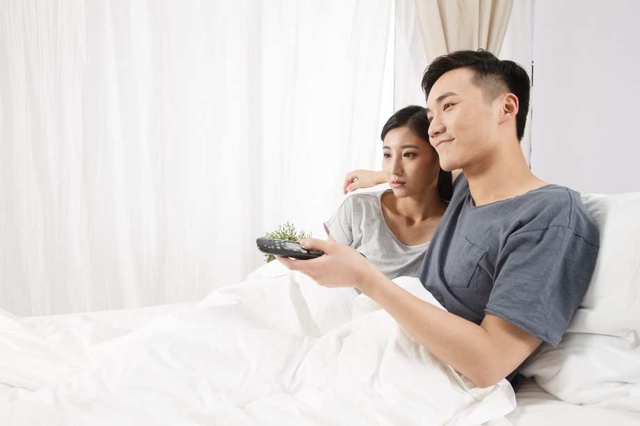 青年情侣坐着床上看电视 青年情侣坐着床上看电视