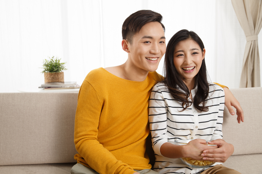 青年情侣坐着沙发上看电视