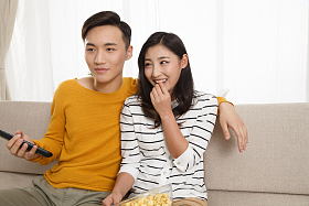 青年情侣坐着沙发上看电视