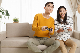 青年情侣坐着沙发上玩游戏