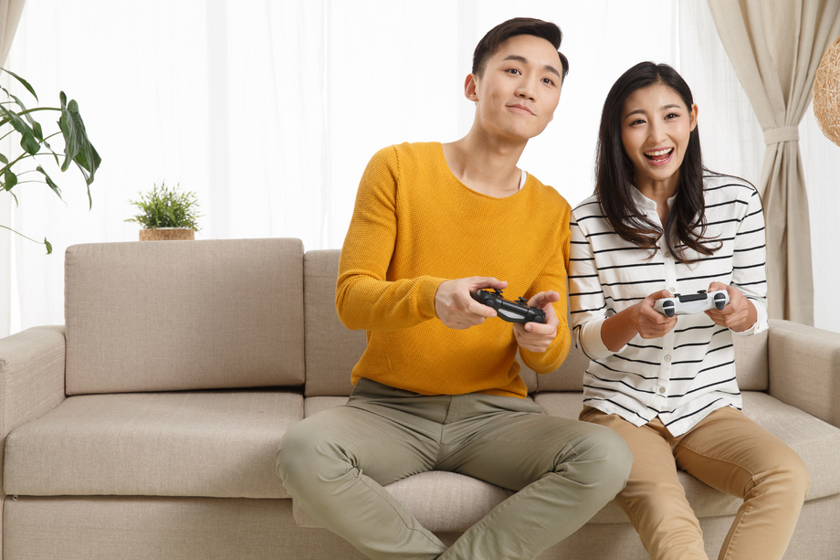青年情侣坐着沙发上玩游戏