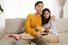 青年情侣坐着沙发上看电视