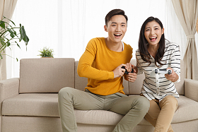 青年情侣坐着沙发上玩游戏照片