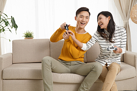 青年情侣坐着沙发上玩游戏