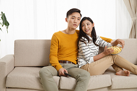 青年情侣坐着沙发上看电视