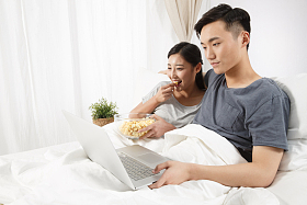 青年情侣坐着床上看电脑图片
