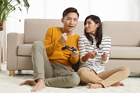 青年情侣坐着沙发上玩游戏图片