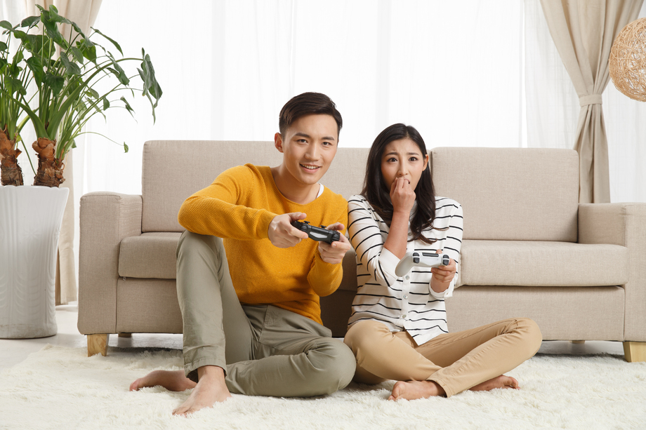 青年情侣坐着沙发上玩游戏