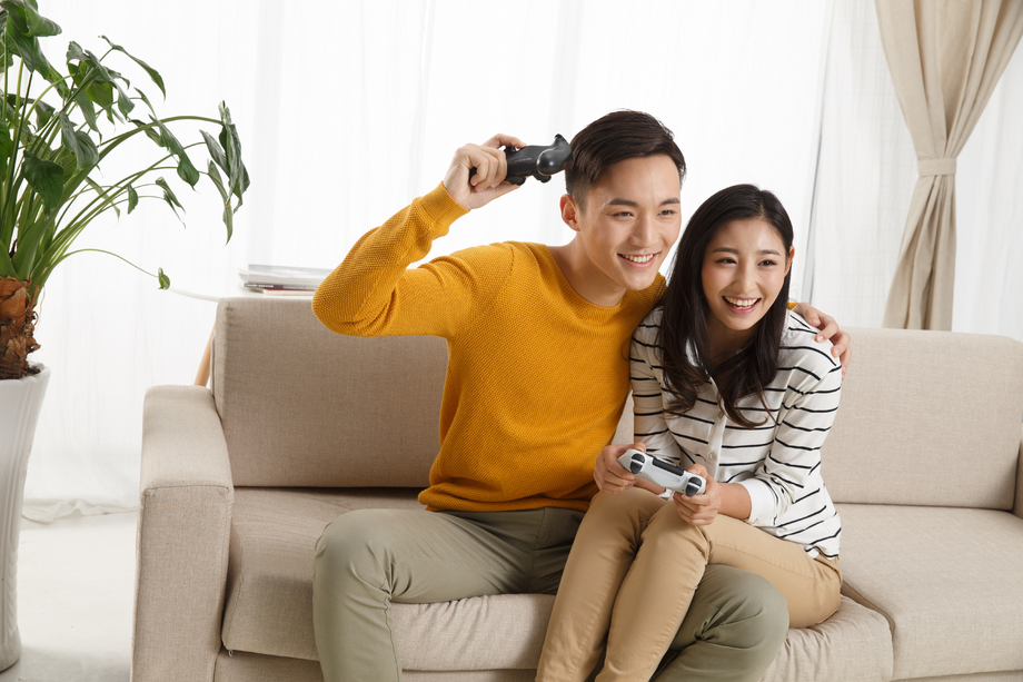 青年情侣坐着沙发上玩游戏照片