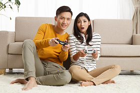 青年情侣坐着沙发上玩游戏图片