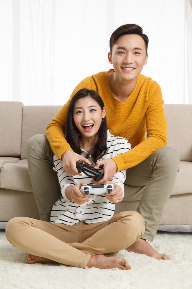 青年情侣坐着沙发上玩游戏图片