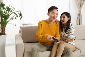 青年情侣坐着沙发上玩游戏图片