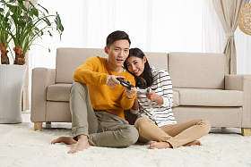 青年情侣坐着沙发上玩游戏照片