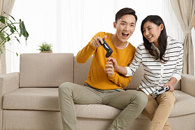 青年情侣坐着沙发上玩游戏照片