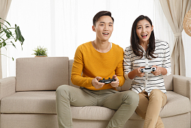 青年情侣坐着沙发上玩游戏图片