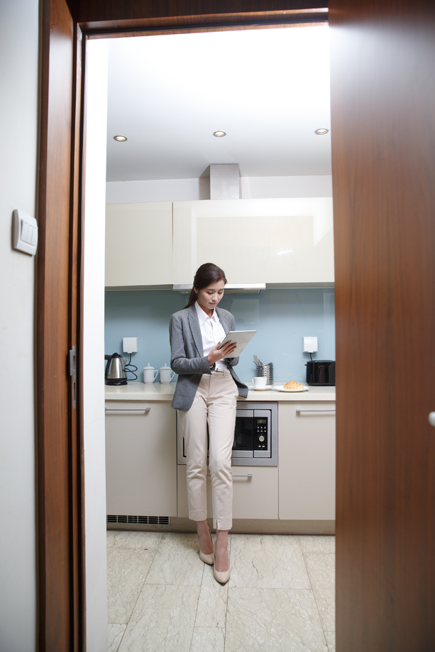 青年女人在厨房使用平板电脑 青年女人在厨房使用平板电脑