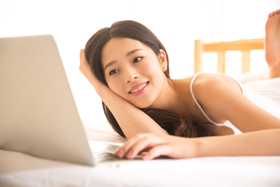 青年女人在卧室使用电脑