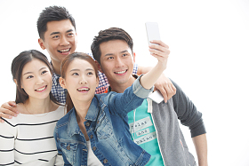 四个的大学生使用手机拍照图片
