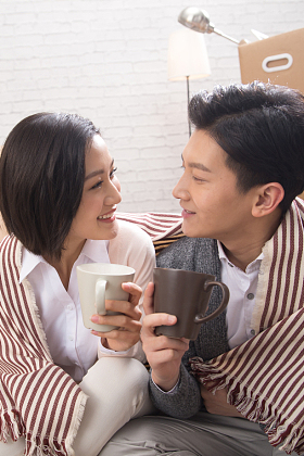 年轻夫妇坐在地板上喝水