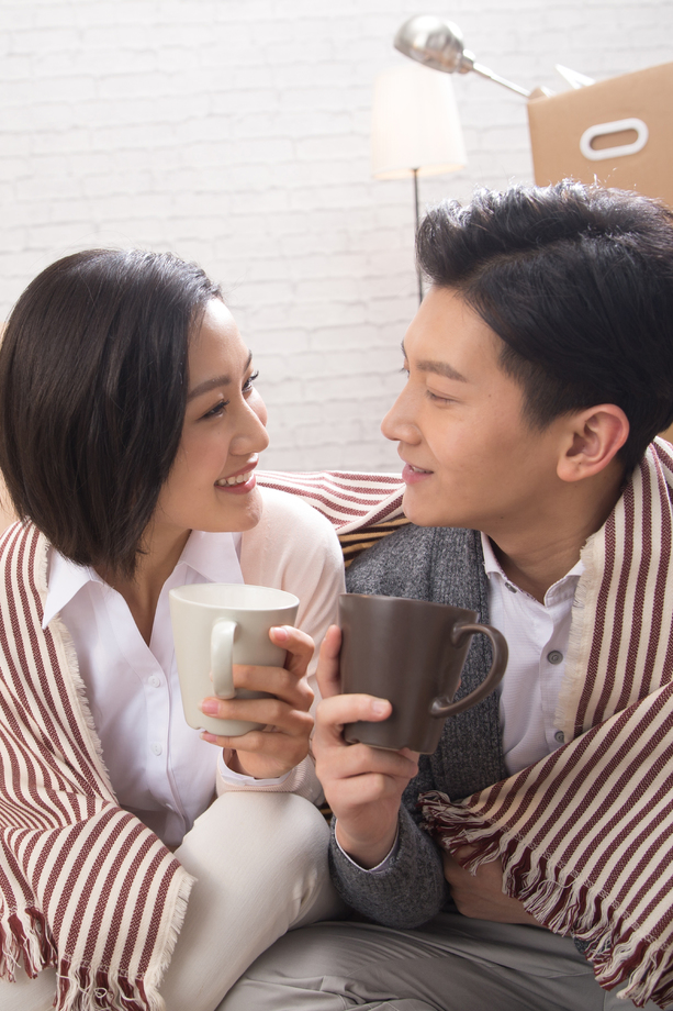 年轻夫妇坐在地板上喝水 年轻夫妇坐在地板上喝水